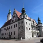 Renesansowy Ratusz w Brzegu z wysokimi wieżami zegarowymi i charakterystycznymi arkadami w przyziemiu, widok frontalny na rynku