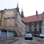 Ulica Jezuitów w Brzegu z widokiem na barokowy kościół jezuitów, zabytkowe kamienice i parkingi, historyczna zabudowa starego miasta