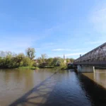 Panorama Brzegu i rzeki Odry widziana z Mostu Piastowskiego, stalowa konstrukcja mostu i zielone brzegi rzeki