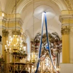 Wnętrze kościoła św. Wawrzyńca w Głuchołazach z barokowym ołtarzem, żyrandolami i wstęgami zawieszonymi pod sklepieniem