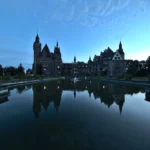 Zamek w Mosznej o zmierzchu, oświetlony ciepłym światłem na tle granatowego nieba blue hour
