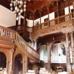 Wnętrze zamku w Mosznej z reprezentacyjną salą, ozdobnymi schodami i drewnianymi boazeriami