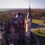 Zamek w Mosznej z lotu ptaka, ujęcie z drona pokazujące pałac i otaczający go park