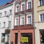 Kamienica przy Rynku 22 w Prudniku sfotografowana w sierpniu 2018 roku, z odnowioną fasadą i witrynami na parterze