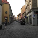 Ulica Ratuszowa w Prudniku z zabytkowymi kamienicami i zaparkowanymi samochodami