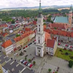Rynek w Prudniku z ratuszem pośrodku placu i kamienicami tworzącymi pierzeję rynku
