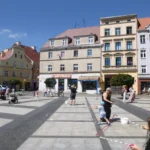 Rynek w Brzegu latem z fontannami, kolorowymi kamienicami i przechodniami spacerującymi po wybrukowanym placu