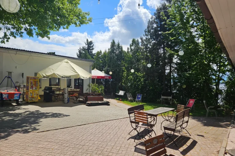 OW Grek - taras rekreacyjny ze stołami, ławkami i grami przy restauracji Grek nad jeziorem