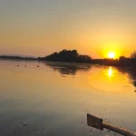 Jezioro Otmuchowskie - zachód słońca nad jeziorem z zielonym brzegiem, OW Grek